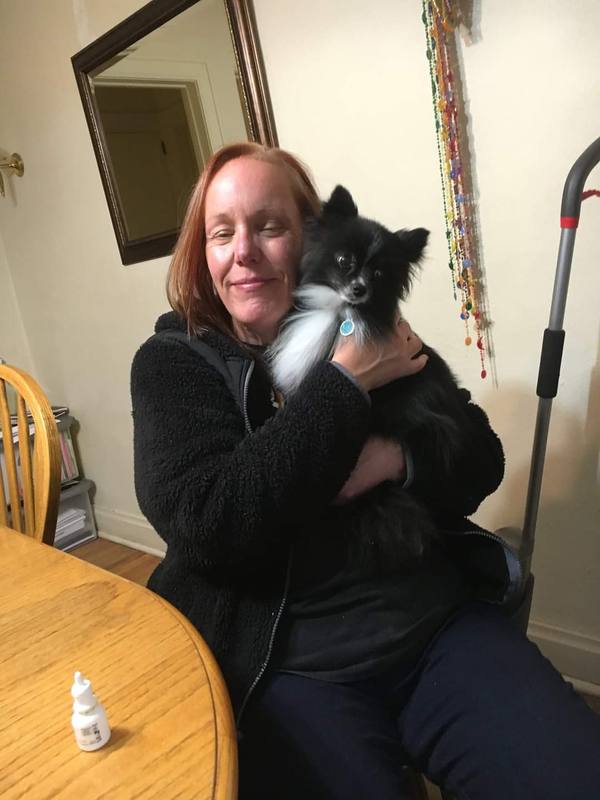 Dayna holding a small black and white dog she is caring for